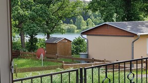 A view of a lakeside property with a wooden shed and a small building, a fenced area, and a metal gate. - Quietly located bungalow with a view of the dam (Zeulenroda-Triebes)