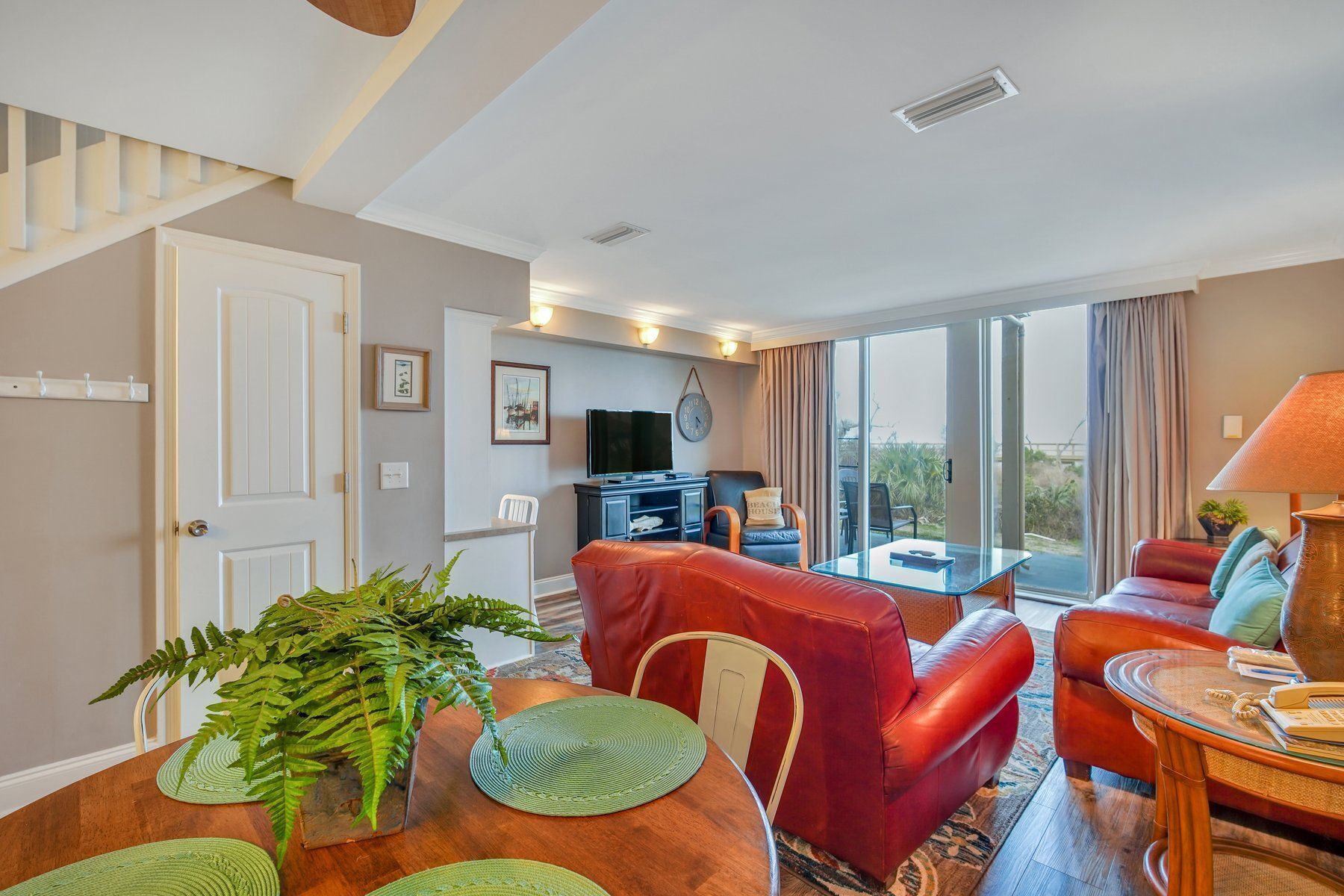 A spacious living area with a dining table, red leather sofas, and a television.