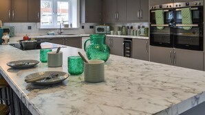 Una cocina moderna con encimera de mármol, electrodomésticos de acero inoxidable y un amplio ventanal que proporciona luz natural.