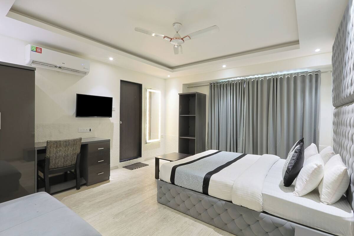 A modern bedroom with a bed, desk, chair, and a television.