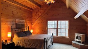 Une chambre confortable dans un chalet en bois, avec un lit, des lampes de chevet, un radiateur et une grande fenêtre.