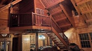 L’intérieur d’une cabane en bois comprend une chambre à coucher située en mezzanine, un coin repas et un escalier.