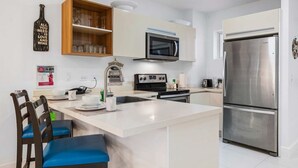Een moderne keuken met een centraal eiland, roestvrijstalen apparatuur en een houten kastje boven de magnetron.