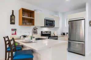A modern kitchen with a central island, stainless steel appliances, and a wooden cabinet above the microwave. - Prime Location! Beach near 2BR Condo w/ Pool View (Noord)