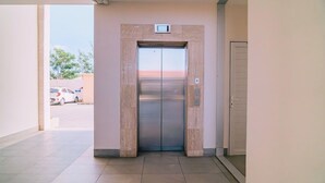 Een moderne lift met een zichtbaar bedieningspaneel en een deur met een hendel.