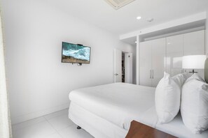 A bedroom with a bed, a television mounted on the wall, and a wardrobe. - 2BR Condo w/ Pool-View Balcony near Palm Beach (Noord)