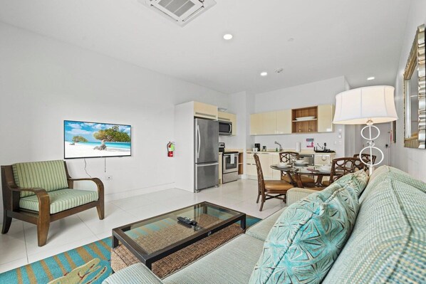 A modern living room with a sofa, coffee table, and a television mounted on the wall.