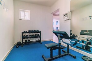 A gym with exercise equipment, a dumbbell rack, and a bench. - Resort-Style Amenities! 1BR Condo with Pool Access (Noord)