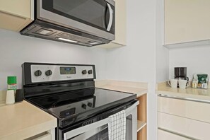 A compact kitchen with a stove, microwave, and a coffee maker on the counter.