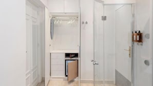 A walk-in closet with a mirrored closet rod, a wooden cabinet, and a sliding door closet. - Primus Monti Suites  (Rome)
