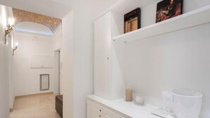 A modern bathroom with white cabinetry, a towel rack, and a shelf with decorative items. - Primus Monti Suites  (Rome)