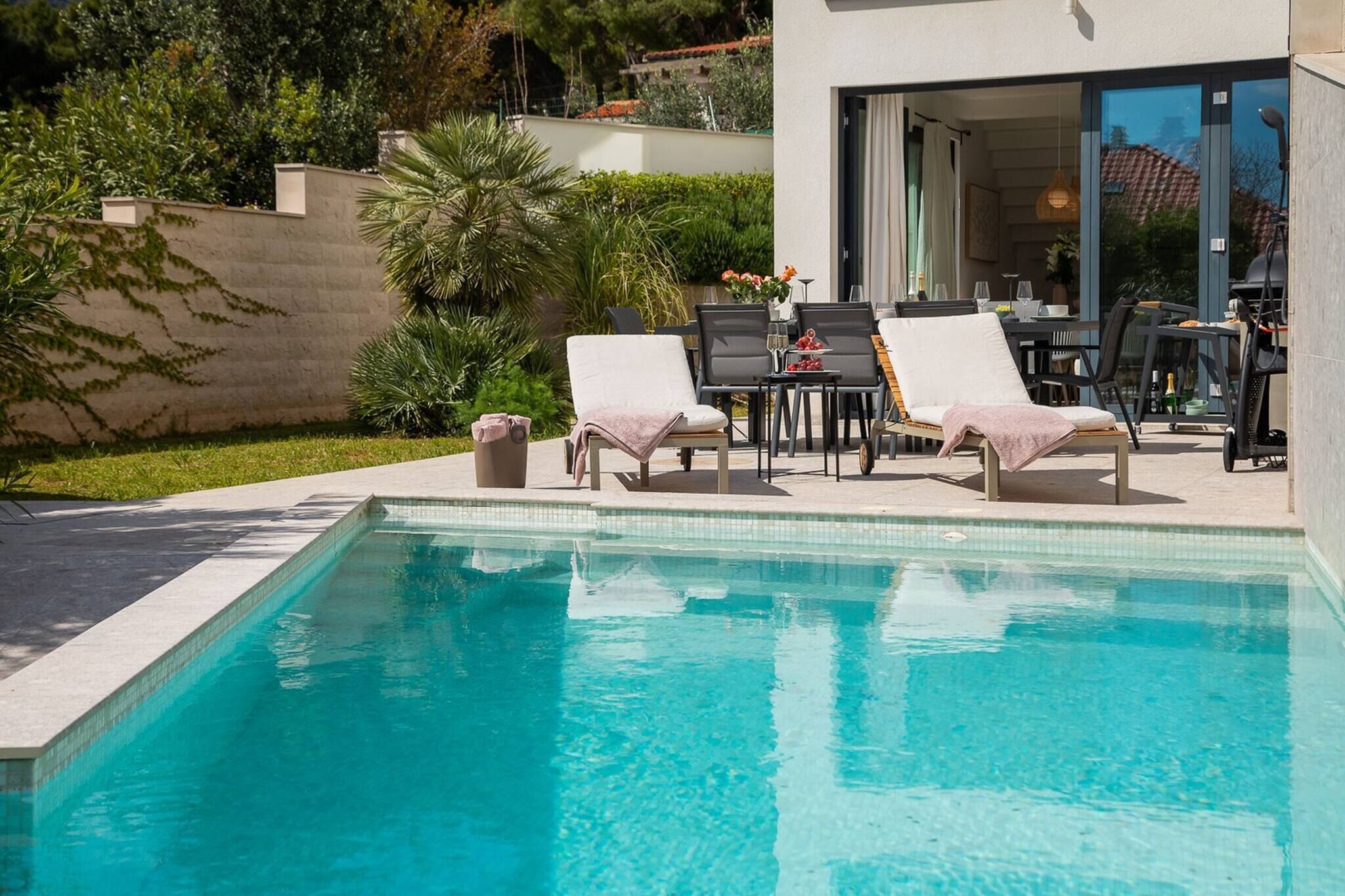 A swimming pool with lounge chairs, a table with drinks, and a patio area.
