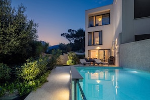 A modern building with a swimming pool, outdoor seating, and a well-maintained garden.