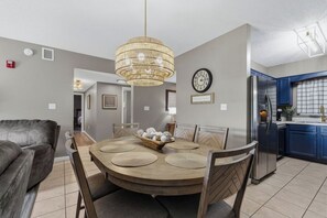 A dining area with a round wooden table, chairs, and a chandelier.
