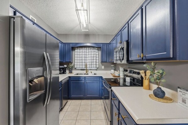 A modern kitchen with stainless steel appliances, blue cabinets, and a central island.