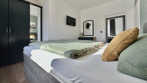 Un dormitorio con cama, armario, espejo y televisor.