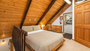 A bedroom with a wooden ceiling, a bed, a nightstand, a chair, a dresser, and a door. - Enchantments Hike Nearby | Views | Hot Tub | BBQ (Leavenworth)