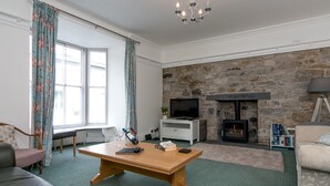 A cozy living room with a stone fireplace, a television, and a comfortable seating area.
