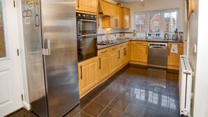 A modern kitchen with stainless steel appliances, wooden cabinets, and a large window providing natural light.