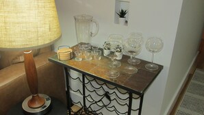 A bar area with a variety of glasses and a pitcher on a table, a lamp, and a small potted plant. - Renovated Condo, Avon Colorado, River Views and walk to Beaver Creek Shuttle (Avon)