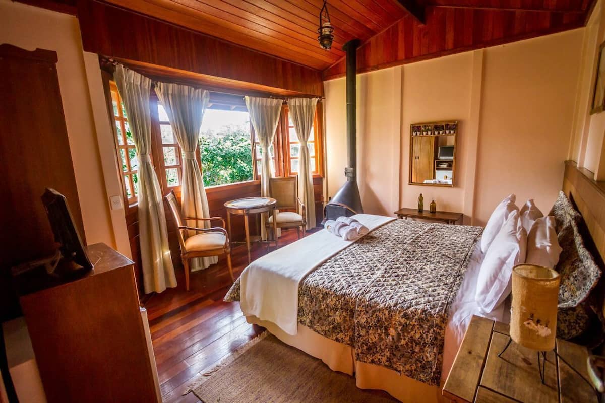 A cozy room with a bed, a small table, a chair, and a window with curtains.