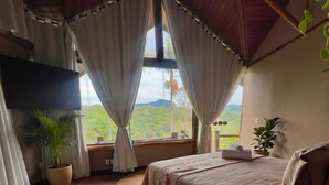 A bedroom with a bed, a desk, and a window with curtains. - Pousada Apoema (Petrópolis)