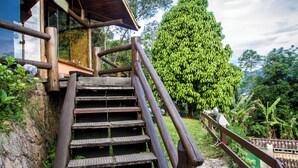 A set of wooden stairs leading up to a wooden structure with a roof, surrounded by greenery and trees. - Pousada Apoema (Petrópolis)