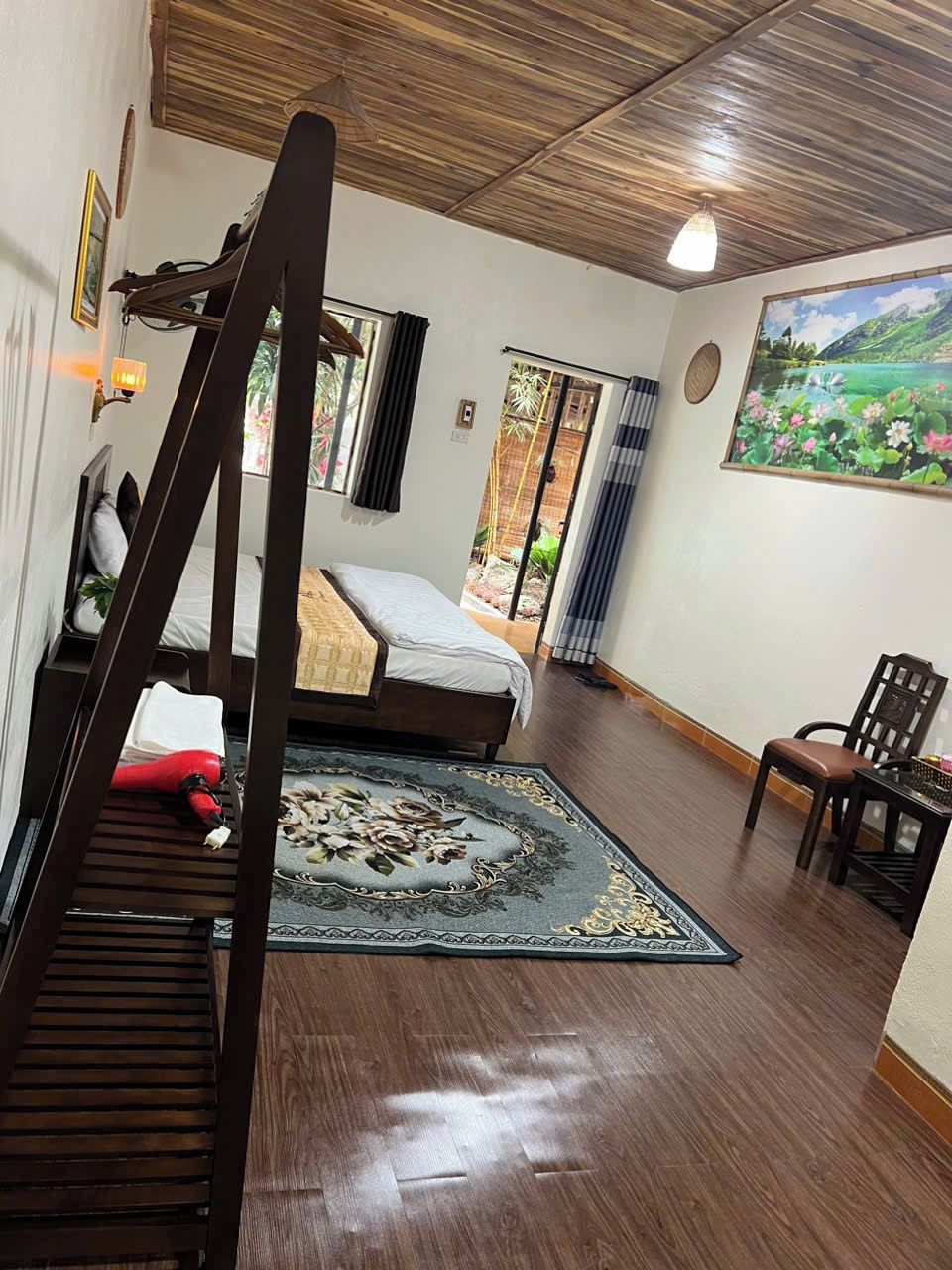 Une chambre à coucher avec un plafond en bois, un lit, une chaise, une table et un tableau représentant un paysage.