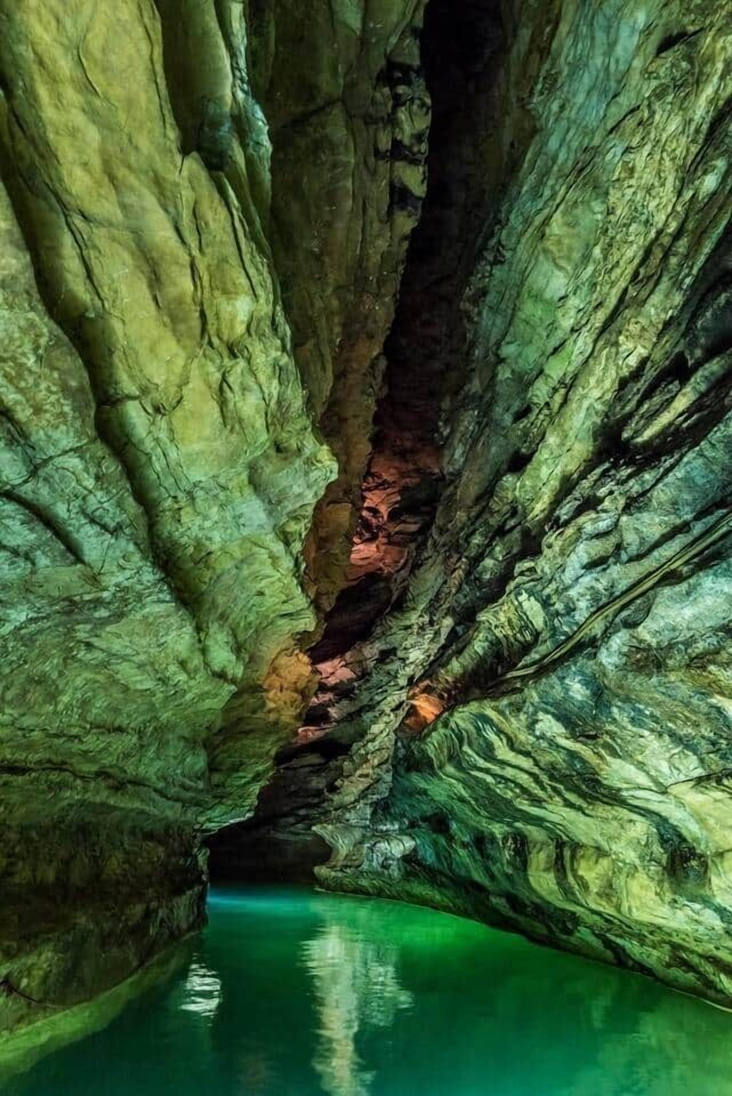 Une grotte avec des formations rocheuses naturelles et une étendue d’eau.