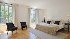 Una camera da letto con un letto, due sedie, un comodino e una finestra con tende.