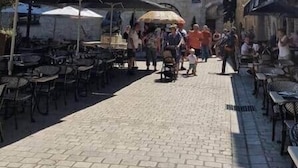 Una strada acciottolata con un edificio storico, caratterizzato da una torre e finestre ad arco.