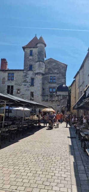 Una calle adoquinada con un edificio histórico que presenta una torre y ventanas arqueadas.
