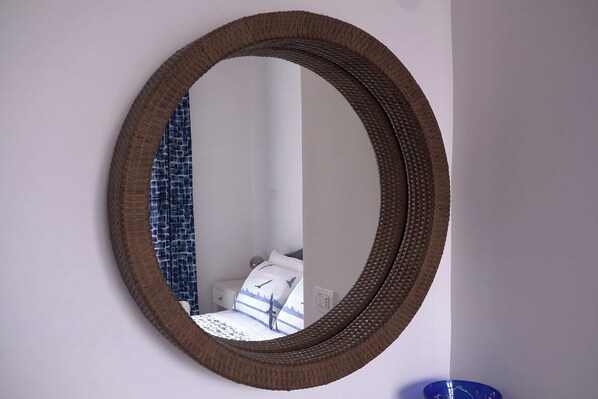 A round mirror with a woven frame on a wall.