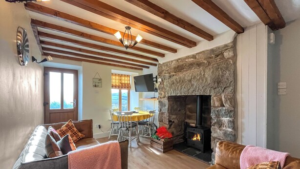 A cozy living room with a stone fireplace, wooden beams, and a comfortable seating area. - 2 bedroom accommodation in Betws-Y-Coed (Betws-Y-Coed)