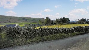 A rural landscape with a stone wall, a road, and rolling hills in the background. - 2 bedroom accommodation in Betws-Y-Coed (Betws-Y-Coed)