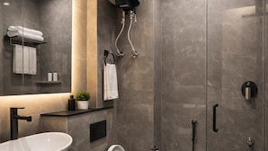 A modern bathroom with a large vessel sink, a toilet, a shower enclosure, and a wall-mounted heater. - Hotel The Rise (New Delhi)