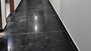 A corridor with a shiny black floor, white walls, and a fire extinguisher on the right. - Hotel The Rise (New Delhi)