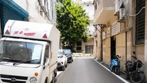 A narrow urban street with parked vehicles and buildings on either side. - Hotel The Rise (New Delhi)
