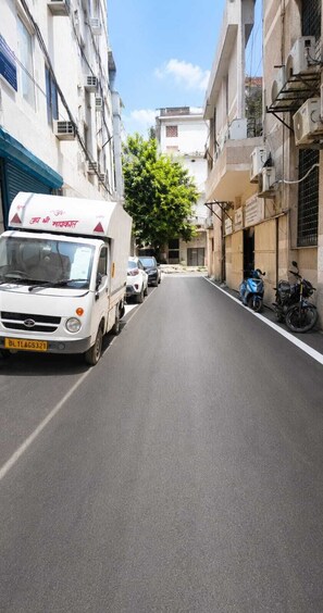 A narrow urban street with parked vehicles and buildings on either side.