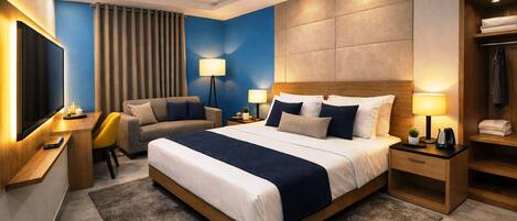 A modern hotel room with a large bed, a desk, a chair, a TV, and a wardrobe.