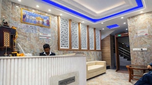 A reception area with a marble floor, a reception desk, a sofa, and a staircase. - Hotel The Rise (New Delhi)