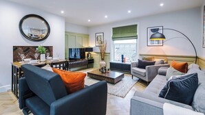 A modern living room with a sofa, coffee table, and TV. - Charming 2-bedroom Flat in York - Sleeps 6 (York)