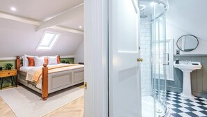 A bedroom with a bed, bedside table, and a small window. The image also shows a bathroom with a sink, mirror, and shower. - Charming 2-bedroom Flat in York - Sleeps 6 (York)