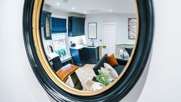 A modern kitchen with dark cabinetry, a white countertop, and a window. - Charming 2-bedroom Flat in York - Sleeps 6 (York)