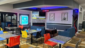 Un espace de détente moderne avec des tables et des chaises, un écran de télévision diffusant les actualités et une cheminée.