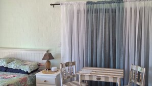 Ett sovrum med en säng, ett nattduksbord med en lampa, en stol och ett litet bord med papper på.