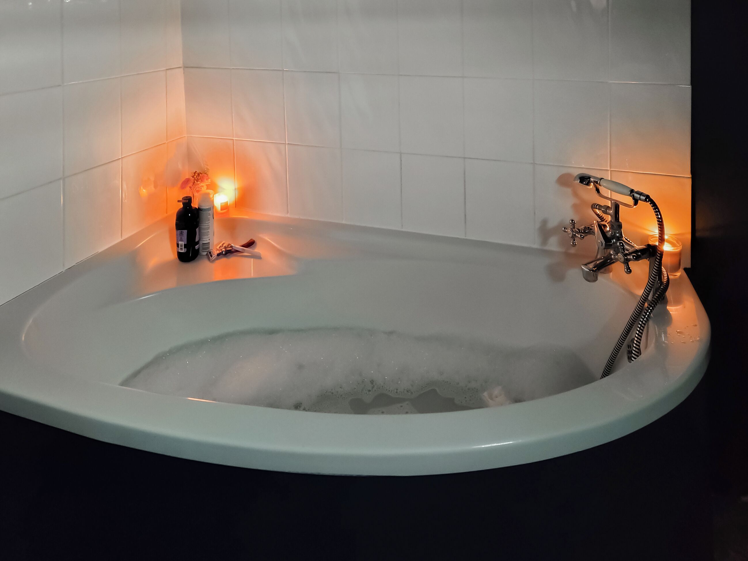 A bathtub with a modern faucet and a candle on the side.