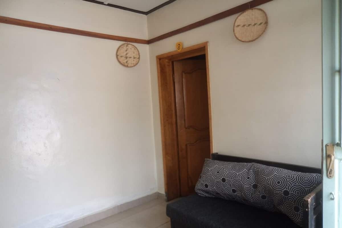 A room with a sofa, a wooden door, and a wall clock.