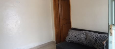 A room with a sofa, a wooden door, and a wall clock.