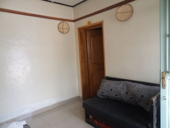 Una habitación con sofá, puerta de madera y un reloj de pared.